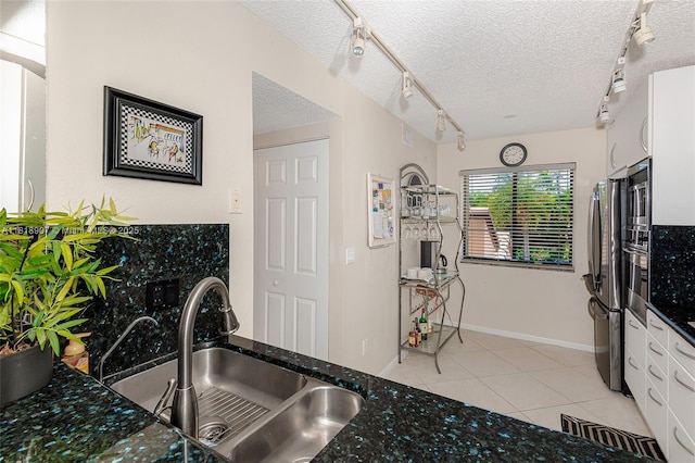 240 Captains Walk Unit 5110, Delray Beach, FL 33483 - kitchen with track lighting, white cabinets, a textured ceiling, dark stone countertops, and freestanding refrigerator