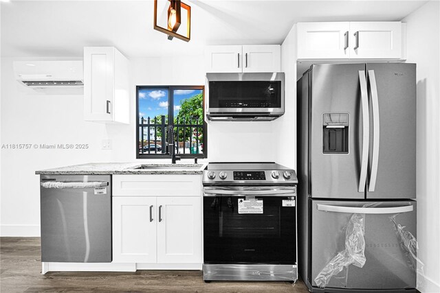 1805 SW 4th St, Miami, FL 33135 - kitchen with appliances with stainless steel finishes, an AC wall unit, dark wood-style flooring, and white cabinets