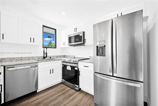 1805 SW 4th St, Miami, FL 33135 - kitchen featuring appliances with stainless steel finishes, wood finished floors, white cabinetry, light stone countertops, and recessed lighting