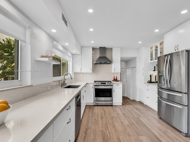 1130 NE 91st Ter, Miami Shores, FL 33138 - kitchen with stainless steel appliances, wall chimney range hood, white cabinetry, light wood finished floors, and recessed lighting