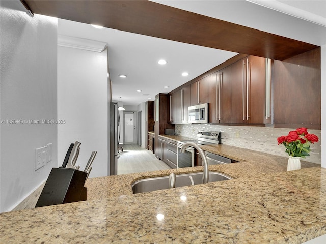 9933 NW 49th Ter, Doral, FL 33178 - kitchen with appliances with stainless steel finishes, light stone counters, decorative backsplash, recessed lighting, and light wood-style floors