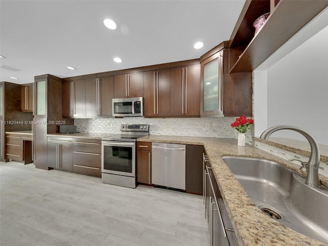 9933 NW 49th Ter, Doral, FL 33178 - kitchen with stainless steel appliances, light stone counters, backsplash, glass insert cabinets, and dark brown cabinets
