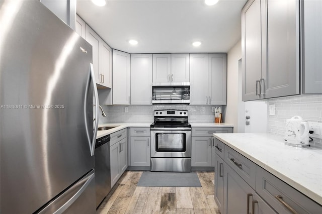 2781 Taft St Unit 308, Hollywood, FL 33020 - kitchen featuring stainless steel appliances, gray cabinetry, light wood-style floors, decorative backsplash, and recessed lighting