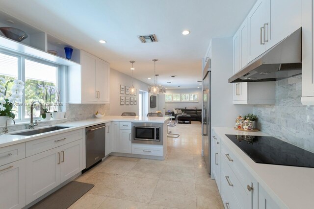 11900 SW 72nd Pl, Pinecrest, FL 33156 - kitchen with stainless steel appliances, under cabinet range hood, a peninsula, backsplash, and recessed lighting