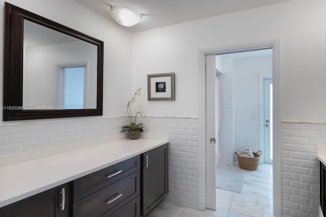 11900 SW 72nd Pl, Pinecrest, FL 33156 - bathroom featuring vanity, tile walls, wainscoting, and marble look tile flooring