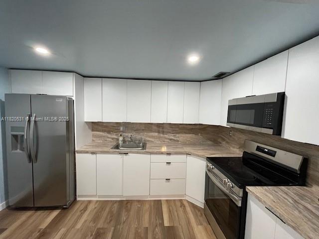 1475 NE 125th Ter Unit 614K, North Miami, FL 33161 - kitchen featuring appliances with stainless steel finishes, light wood finished floors, white cabinetry, and recessed lighting