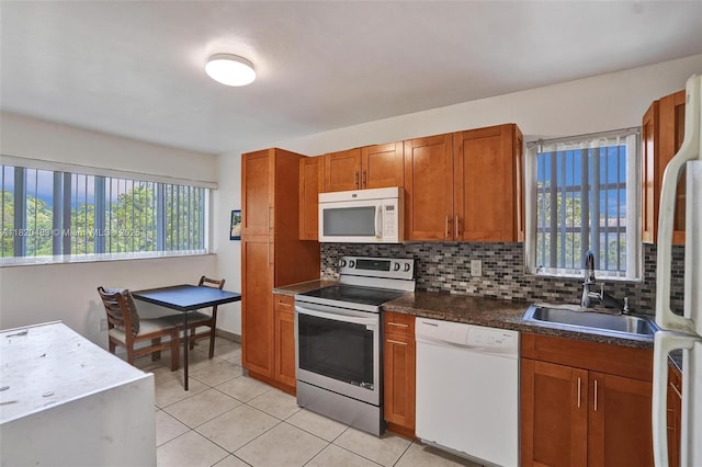8351 Sands Point Blvd Unit A301, Tamarac, FL 33321 - kitchen with white appliances, brown cabinets, backsplash, light tile patterned floors, and dark countertops