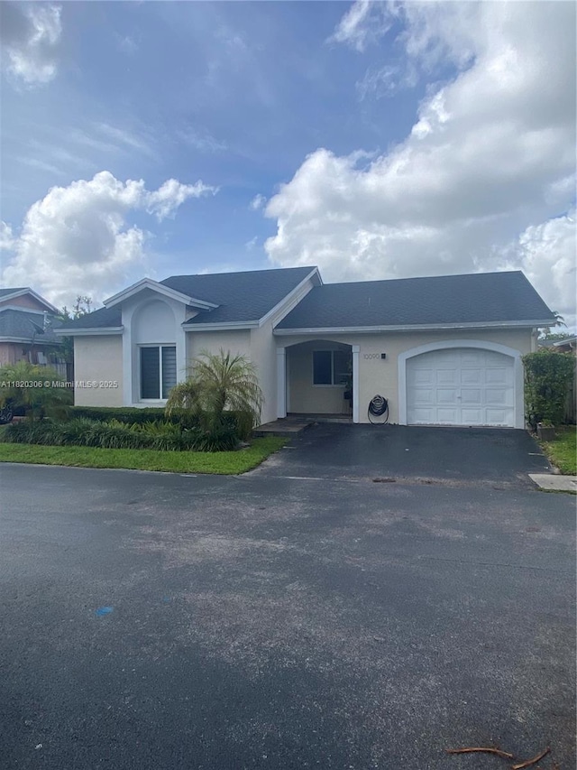 10090 NW 57th St, Doral, FL 33178 - view of front facade with an attached garage, stucco siding, and asphalt driveway