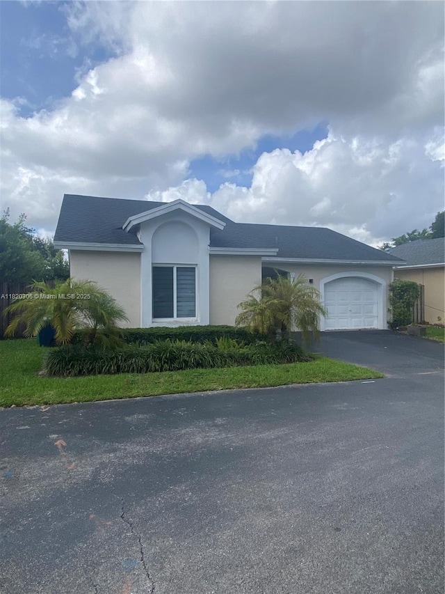 10090 NW 57th St, Doral, FL 33178 - view of front of house with stucco siding, a garage, and asphalt driveway