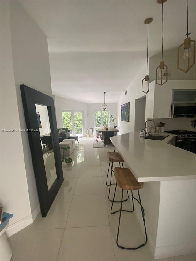 10090 NW 57th St, Doral, FL 33178 - kitchen featuring a kitchen bar, light tile patterned floors, pendant lighting, open floor plan, and light countertops