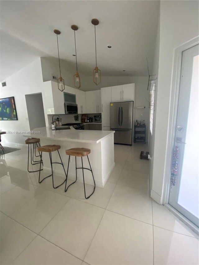 10090 NW 57th St, Doral, FL 33178 - kitchen with appliances with stainless steel finishes, vaulted ceiling, white cabinets, a kitchen breakfast bar, and decorative light fixtures