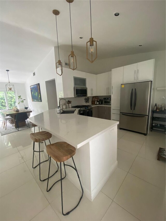 10090 NW 57th St, Doral, FL 33178 - kitchen featuring stainless steel appliances, a peninsula, a breakfast bar area, light tile patterned flooring, and white cabinets