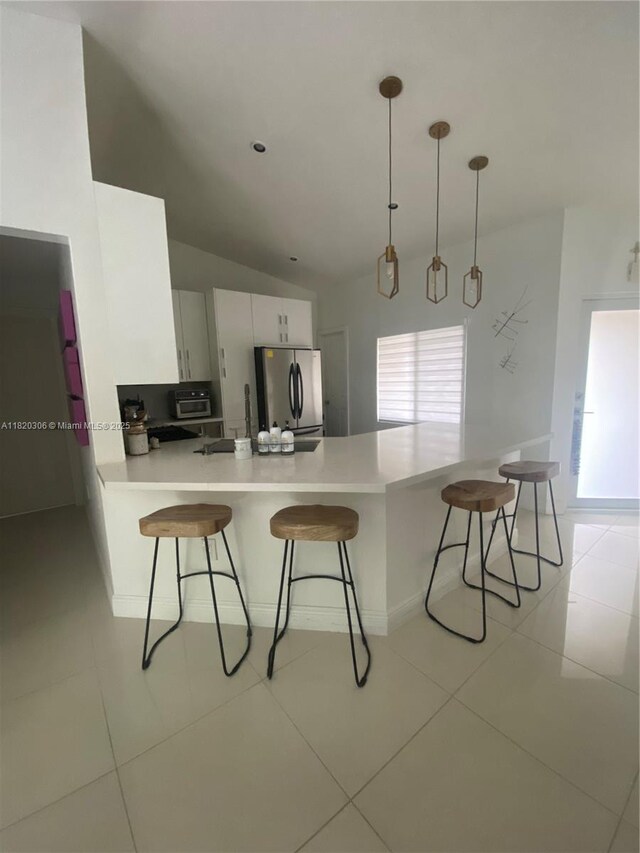 10090 NW 57th St, Doral, FL 33178 - kitchen featuring freestanding refrigerator, a kitchen breakfast bar, a peninsula, light countertops, and vaulted ceiling