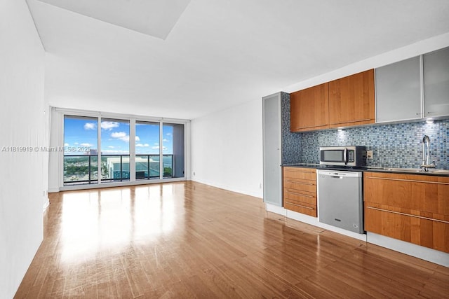100 Bayview Dr Unit 1223, Sunny Isles Beach, FL 33160 - kitchen with stainless steel appliances, brown cabinets, floor to ceiling windows, light wood-style floors, and tasteful backsplash