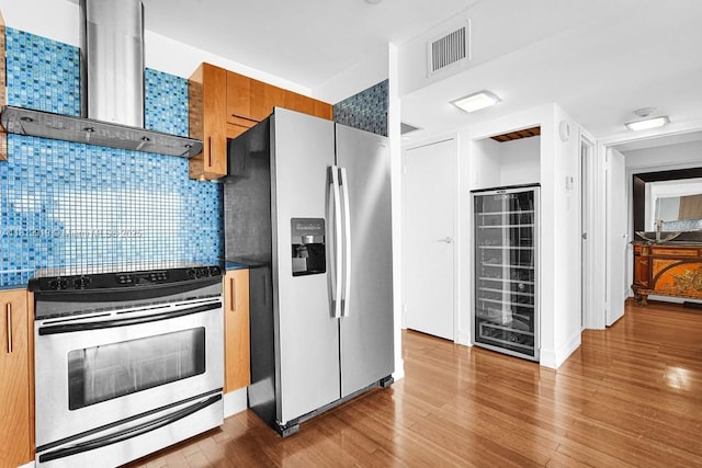 100 Bayview Dr Unit 1223, Sunny Isles Beach, FL 33160 - kitchen with stainless steel appliances, wall chimney exhaust hood, wine cooler, wood finished floors, and backsplash