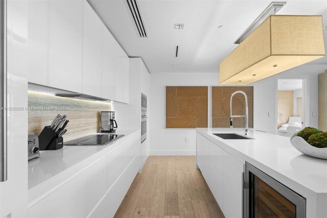 102 24th St Unit Ph-1706, Miami Beach, FL 33139 - kitchen featuring modern cabinets, white cabinets, black electric cooktop, and beverage cooler