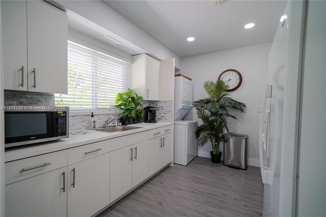 8390 SW 64th St, Miami, FL 33143 - kitchen featuring stainless steel microwave, light wood-type flooring, decorative backsplash, white cabinets, and light countertops