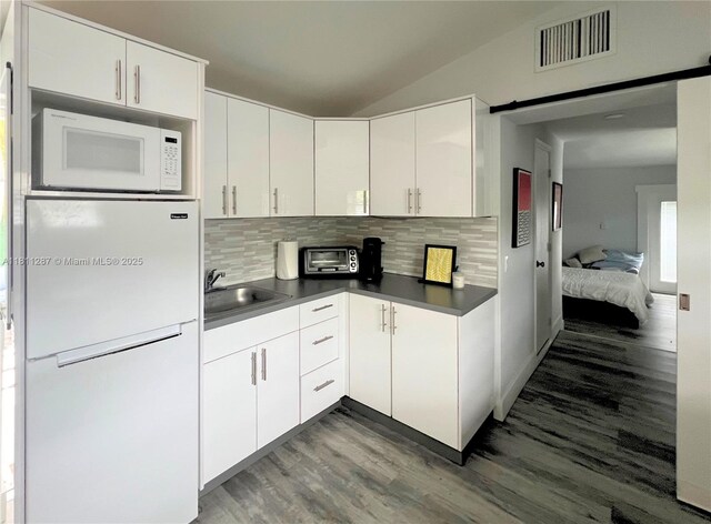 8390 SW 64th St, Miami, FL 33143 - kitchen featuring white appliances, dark wood finished floors, backsplash, dark countertops, and lofted ceiling
