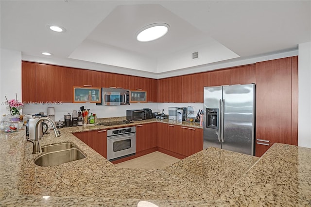 14951 Royal Oaks Ln Unit 803, North Miami, FL 33181 - kitchen featuring appliances with stainless steel finishes, a tray ceiling, light stone countertops, brown cabinets, and recessed lighting