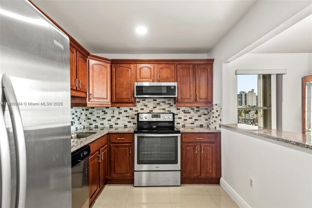 7118 Bonita Dr Unit 405, Miami Beach, FL 33141 - kitchen featuring appliances with stainless steel finishes, tasteful backsplash, light stone counters, light tile patterned floors, and brown cabinetry