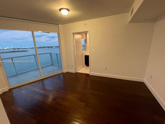 665 NE 25th St Unit 1102, Miami, FL 33137 - spare room featuring wood finished floors, a textured ceiling, and a water view