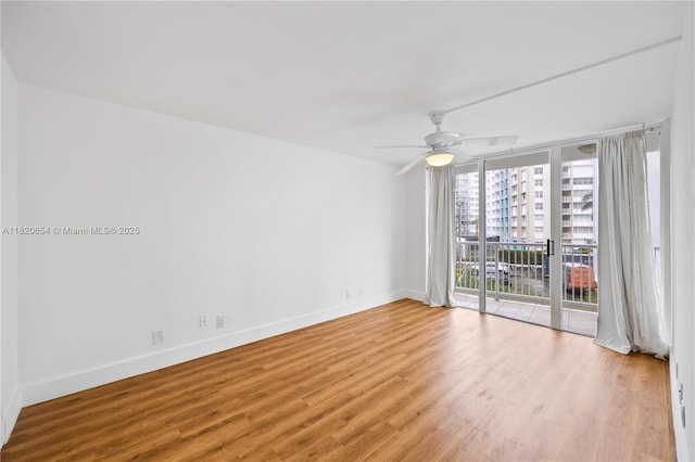 1440 Brickell Bay Unit 307, Miami, FL 33131 - spare room featuring wood finished floors, expansive windows, and a ceiling fan