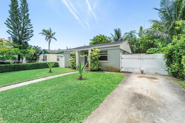 602 El Prado, West Palm Beach, FL 33405 - view of front of home with stucco siding, a gate, a front yard, and concrete driveway