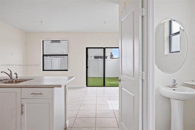 3411 W 112th Ter, Hialeah, FL 33018 - kitchen with white cabinets, light tile patterned floors, and light countertops