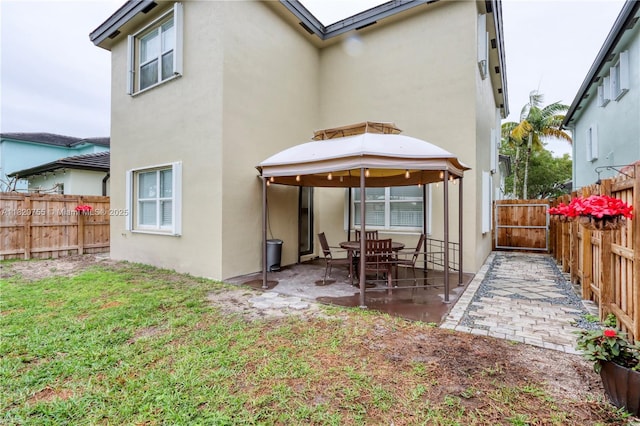 148 NE 36th Avenue Rd, Homestead, FL 33033 - rear view of house featuring stucco siding, a patio area, a fenced backyard, and a gazebo