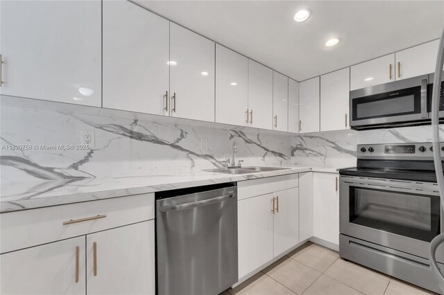 14388 SW 96th Ln, Miami, FL 33186 - kitchen featuring stainless steel appliances, white cabinets, backsplash, light tile patterned floors, and light stone counters