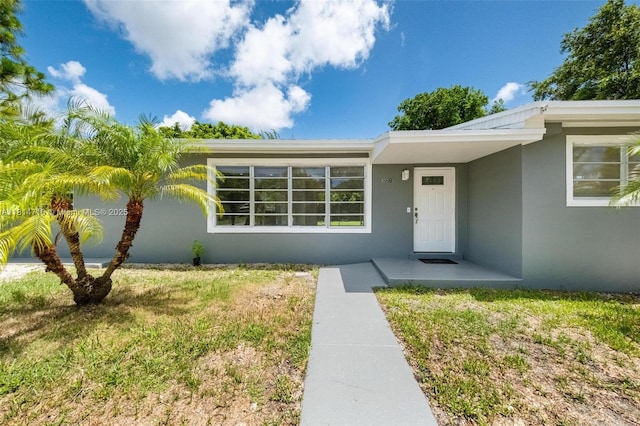 9221 SW 167th Ter, Palmetto Bay, FL 33157 - view of exterior entry featuring stucco siding and a yard