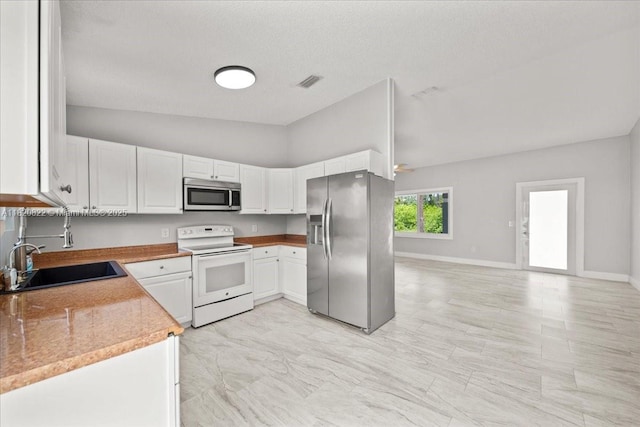 18125 Wintergarden Ave, Port Charlotte, FL 33948 - kitchen with stainless steel appliances, white cabinetry, light countertops, and lofted ceiling