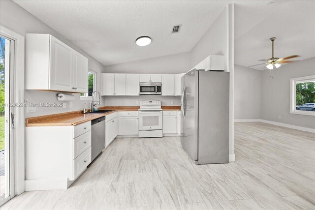 18125 Wintergarden Ave, Port Charlotte, FL 33948 - kitchen featuring appliances with stainless steel finishes, white cabinetry, ceiling fan, lofted ceiling, and light countertops