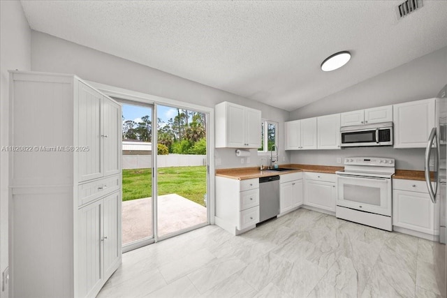 18125 Wintergarden Ave, Port Charlotte, FL 33948 - kitchen with appliances with stainless steel finishes, lofted ceiling, white cabinetry, a textured ceiling, and light countertops