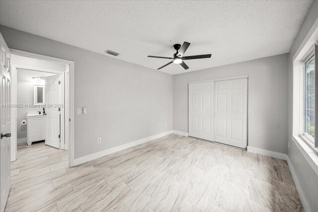 18125 Wintergarden Ave, Port Charlotte, FL 33948 - unfurnished bedroom featuring multiple windows, a textured ceiling, a closet, and a ceiling fan