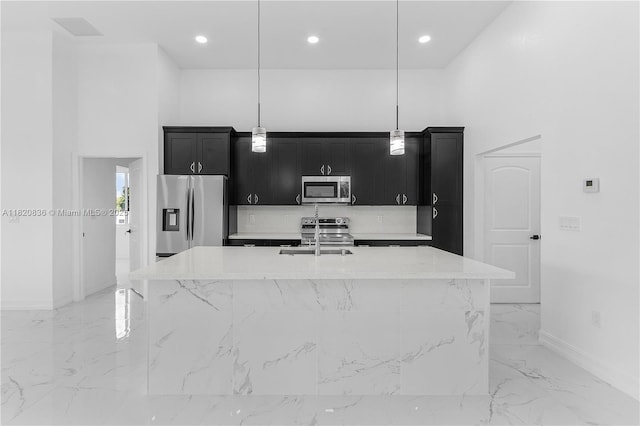 3510 2nd St W, Lehigh Acres, FL 33971 - kitchen with stainless steel appliances, dark cabinets, light marble finish floors, an island with sink, and decorative light fixtures