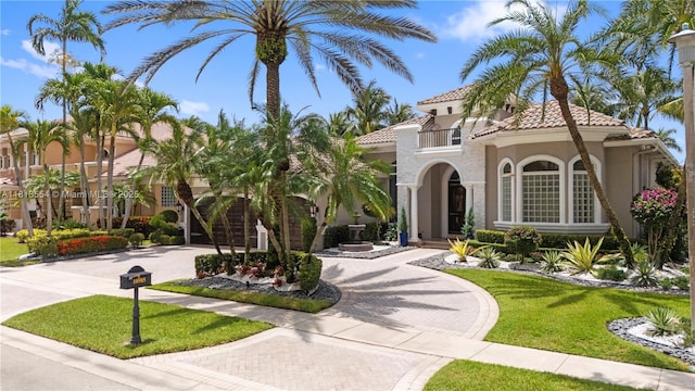 10985 Canary Island Ct, Plantation, FL 33324 - mediterranean / spanish-style house featuring curved driveway, stucco siding, a front yard, a balcony, and a tile roof