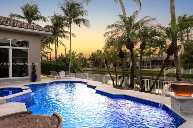 10985 Canary Island Ct, Plantation, FL 33324 - pool at dusk featuring a pool with connected hot tub, a water view, and a patio