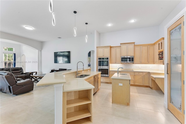 17038 N 61st Pl N, Loxahatchee, FL 33470 - kitchen featuring light brown cabinetry, arched walkways, a kitchen island with sink, appliances with stainless steel finishes, and open floor plan