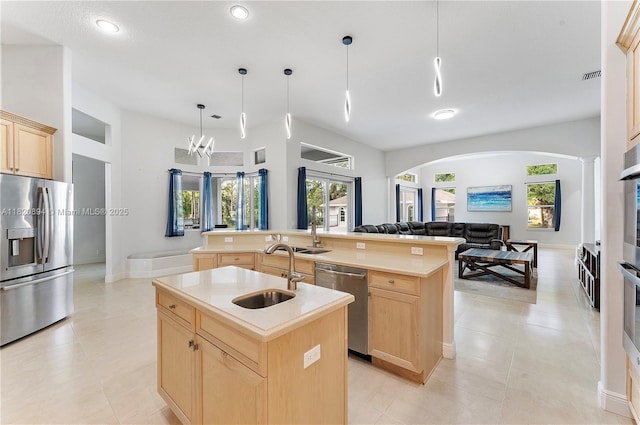 17038 N 61st Pl N, Loxahatchee, FL 33470 - kitchen featuring stainless steel appliances, light brown cabinets, a kitchen island with sink, arched walkways, and open floor plan