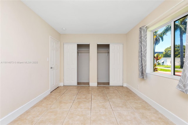 918 NE 6th St, Hallandale Beach, FL 33009 - unfurnished bedroom featuring multiple closets, multiple windows, and light tile patterned floors