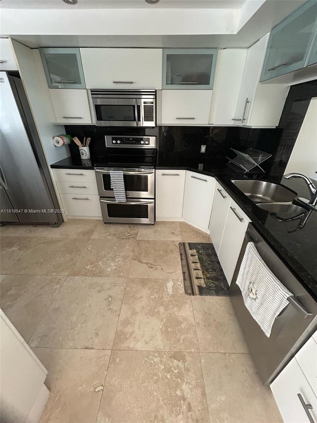 4000 NE 168th St Unit 110A, North Miami Beach, FL 33160 - kitchen with appliances with stainless steel finishes, dark countertops, white cabinets, glass insert cabinets, and decorative backsplash