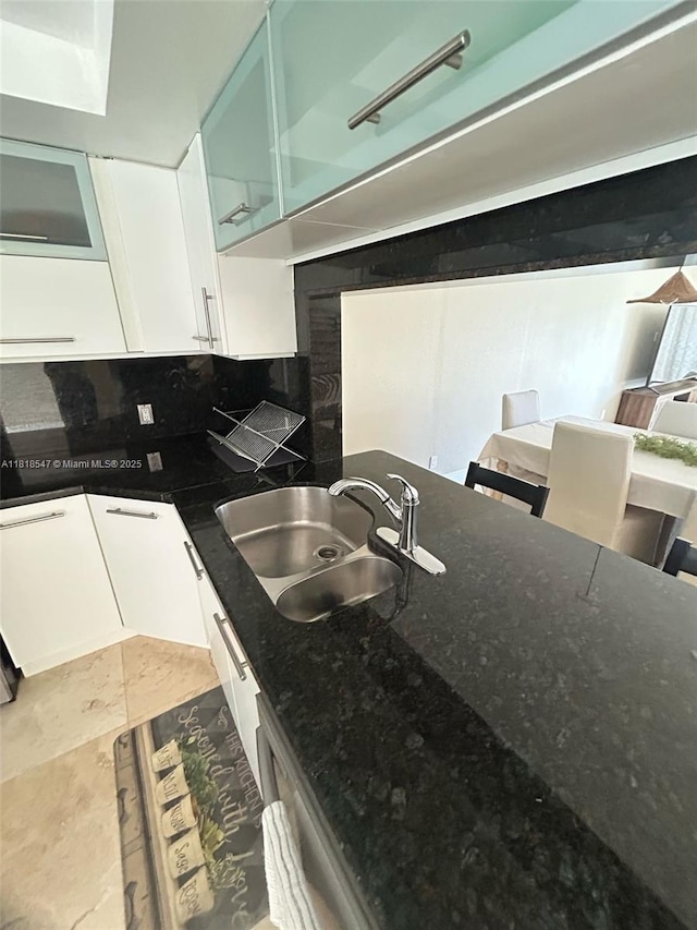 4000 NE 168th St Unit 110A, North Miami Beach, FL 33160 - kitchen featuring white cabinetry, dark stone counters, glass insert cabinets, and backsplash