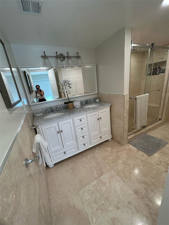 4000 NE 168th St Unit 110A, North Miami Beach, FL 33160 - bathroom featuring a stall shower, double vanity, tile walls, and a wainscoted wall