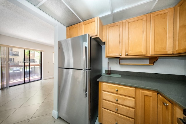 5249 NW 7th St Unit 103, Miami, FL 33126 - kitchen featuring freestanding refrigerator, dark countertops, light tile patterned flooring, and light brown cabinetry