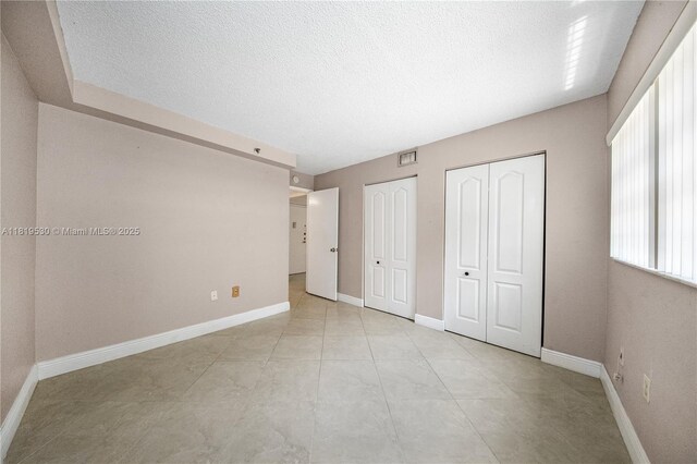 5249 NW 7th St Unit 103, Miami, FL 33126 - unfurnished bedroom with two closets and a textured ceiling