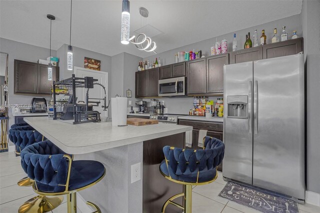 31671 SW 190th Ct, Homestead, FL 33030 - kitchen featuring appliances with stainless steel finishes, light tile patterned floors, light countertops, dark brown cabinetry, and a kitchen bar