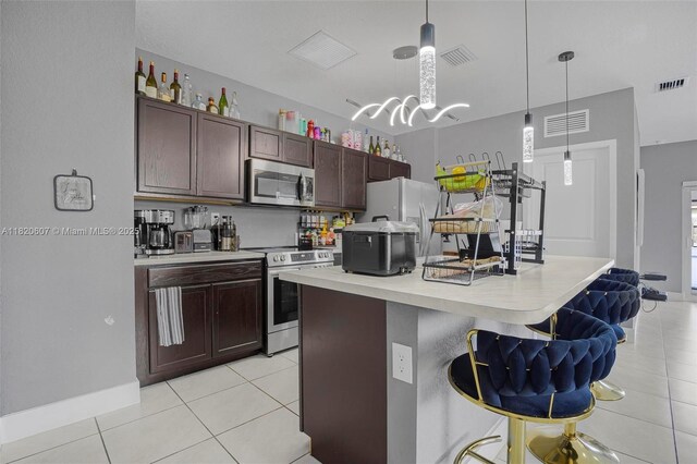 31671 SW 190th Ct, Homestead, FL 33030 - kitchen with appliances with stainless steel finishes, light tile patterned floors, light countertops, an island with sink, and hanging light fixtures