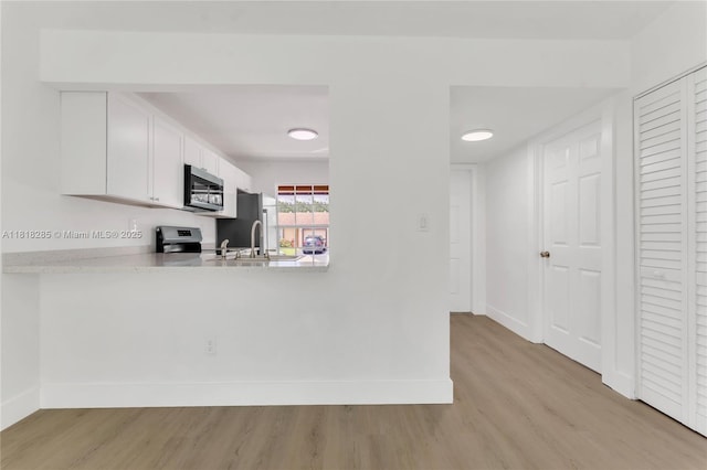 9550 W Heather Ln, Miramar, FL 33025 - kitchen with appliances with stainless steel finishes, light wood finished floors, light countertops, and white cabinetry