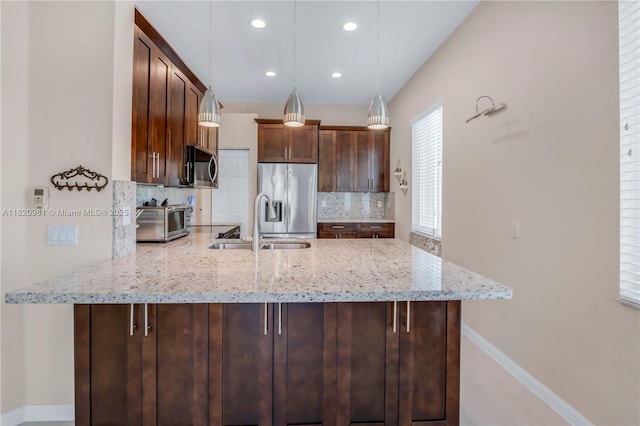1753 Aspen Ln, Weston, FL 33327 - kitchen with appliances with stainless steel finishes, a peninsula, decorative backsplash, light stone counters, and decorative light fixtures
